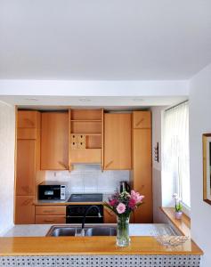 a kitchen with wooden cabinets and a vase of flowers on a table at Apartma AJDA in Velenje