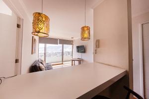 une cuisine avec un comptoir blanc et deux lumières dans l'établissement DEPTO SUITE CENTRO I, à Iquique
