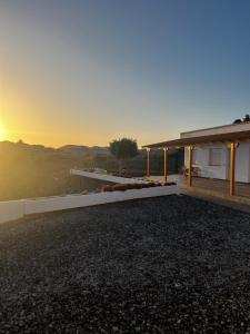 een uitzicht op een huis met de zonsondergang op de achtergrond bij Tantulia Bungalows Tamaragua Tenerife in Arona