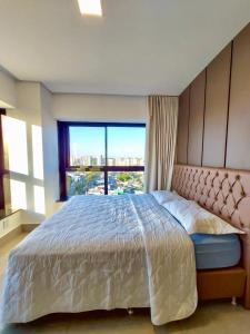 a bedroom with a large bed with a large window at Estúdio Alto 22º andar e Elegante no Edifício Vertigo in Campo Grande