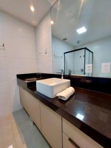 a bathroom with a sink and a large mirror at Estúdio Alto 22º andar e Elegante no Edifício Vertigo in Campo Grande