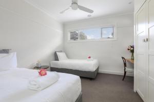 Cette chambre blanche dispose de deux lits et d'une fenêtre. dans l'établissement Sofia Rose House only, à Katoomba