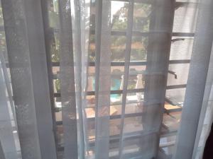 una ventana con cortinas blancas, una mesa y una piscina en Seaesta Studio Diani Beach en Diani Beach