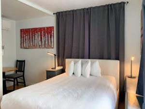 um quarto com uma cama com lençóis brancos e almofadas em Manoir Sainte Genevieve em Cidade de Quebec