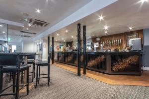 a bar with black stools and a counter with liquor bottles at Best Western The Plough Hotel in Northampton