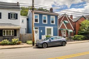 匹茲堡的住宿－Shadyside House - 100 feet to Walnut Street!，停在蓝色房子前面的汽车