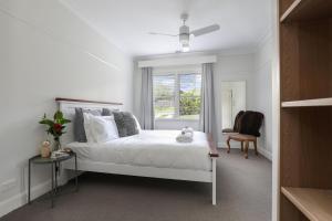 a white bedroom with a bed and a window at Sofia Rose House and Cottage in Katoomba