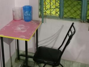 a chair next to a table with a pink table at Welcome paying guest house in Varanasi