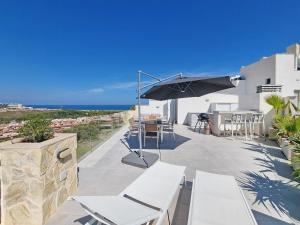 um pátio com uma mesa, cadeiras e um guarda-sol em Sukha Apartments by NRAS em Gran Alacant