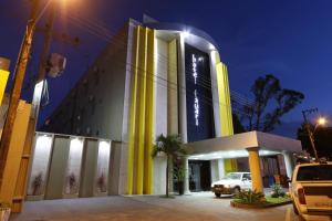 马拉巴Hotel Tauari的一座黄色和白色的建筑,前面有停车位