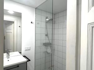 La salle de bains blanche est pourvue d'une douche et d'un lavabo. dans l'établissement Cozy studio in Sv Stepono g., à Vilnius