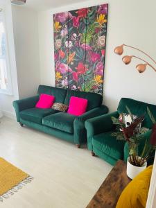 a green couch in a living room with pink pillows at Willow’s Place in Leigh-on-Sea