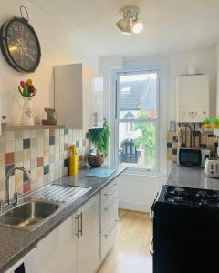 een keuken met een wastafel en een klok aan de muur bij Willow’s Place in Leigh-on-Sea