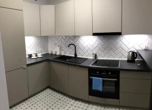 a kitchen with white cabinets and a black stove top oven at Apartament Rzeszów Centrum II in Rzeszów