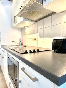 a kitchen with white cabinets and a black counter top at Heart of Grand Place Beautiful Studio in Brussels