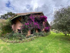 uma casa com flores roxas ao lado em Naturaleza y calma. Finca a 30 minutos de Bogotá. em Facatativa