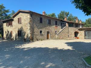 Un grand bâtiment en pierre avec une allée se trouve en face de l'établissement. dans l'établissement Casa Giogo, à Arezzo