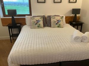 Una cama blanca con toallas y almohadas. en Milo’s Retreat, en Arnside