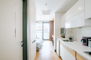 cocina con armarios blancos y pasillo con cama en Cozy Studio Flat w Balcony 10 min to Marmara Forum, en Estambul