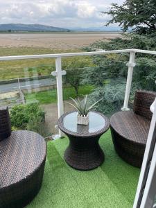 a patio with two chairs and a table with a plant at Watersedge Retreat, views, sunsets, dogs welcome in Sandside