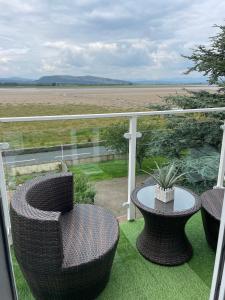a balcony with wicker chairs and a table on the grass at Watersedge Retreat, views, sunsets, dogs welcome in Sandside