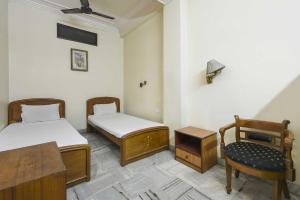 Cette chambre comprend deux lits, une chaise et une table. dans l'établissement OYO Flagship Hotel Ajanta, à Āsansol