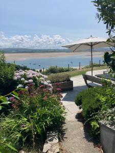 a patio with a bench and flowers and an umbrella at Seaview Cottage in Aberdyfi