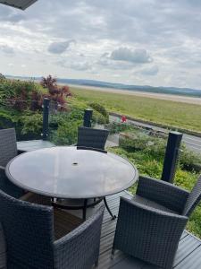 a table and chairs on a deck with a view of the ocean at Watersedge Retreat, views, sunsets, dogs welcome in Sandside