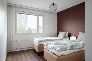 two beds in a room with a window at Moderni ja tilava kolmio + sauna in Kuopio
