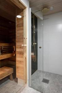 La salle de bains est pourvue d'une douche et d'une porte en verre. dans l'établissement Moderni ja tilava kolmio + sauna, à Kuopio