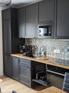 une cuisine avec des armoires noires et un comptoir dans l'établissement "Le Royan" appartement proche gare et plage, à Royan