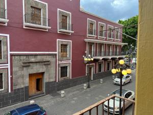 un edificio púrpura con coches aparcados delante de él en Catedral 304, en Puebla