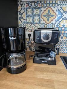 - une cafetière assise sur un comptoir à côté d'un four micro-ondes dans l'établissement "Le Royan" appartement proche gare et plage, à Royan