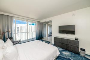 a hotel room with a large bed and a television at Beachfront Luxury 2BR 2BA, Sleeps 6, Resort Access - Horizon by HomeStakes in Fort Lauderdale