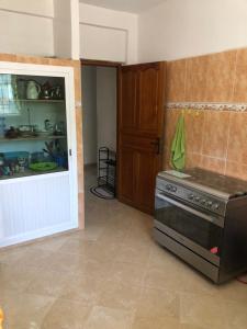 a kitchen with a stove and a door to a room at Vittel Ifrane Large and Beautiful Apartment in Ifrane