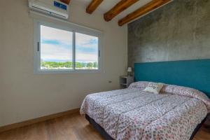 1 dormitorio con 1 cama con cabecero azul y ventana en Casa en chacras de coria en Mendoza