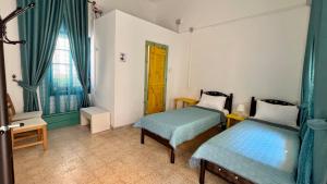 sypialnia z 2 łóżkami, oknem i krzesłem w obiekcie Shazly Inn w mieście Nazaret