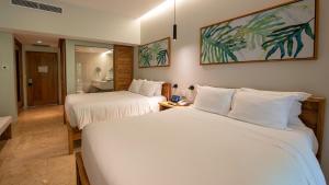 a hotel room with two beds and a bathroom at Tabacón Thermal Resort & Spa in Fortuna