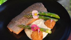 a black plate with a sandwich with flowers and asparagus at Tabacón Thermal Resort & Spa in Fortuna