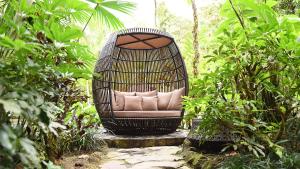 a rattan chair sitting in the middle of a garden at Tabacón Thermal Resort & Spa in Fortuna