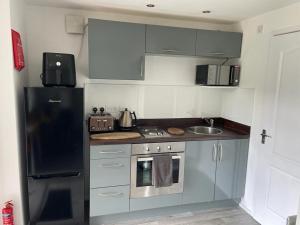 uma pequena cozinha com um frigorífico e um lavatório em Buckshaw Snoozy em Heapey