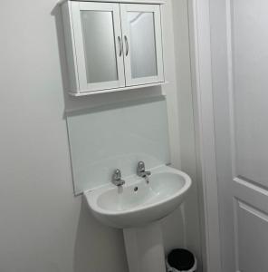 a white bathroom with a sink and a cabinet at Buckshaw Snoozy in Heapey