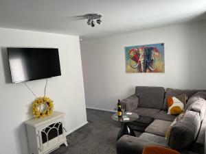 uma sala de estar com um sofá e uma televisão de ecrã plano em Buckshaw Snoozy em Heapey
