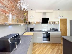 a kitchen with stainless steel appliances and a brick wall at The Yorkshire Hosts - Knights Stay 
