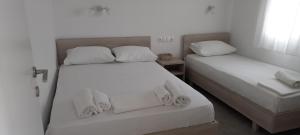 two beds in a room with white sheets and towels at Anna -House Maria Manolaki, 2-Βedrm Apartment in Vourvourou