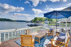 una terraza con sillas, una mesa y una sombrilla en Lake of the Ozarks Vacation Home with Boat Dock en Gravois Mills