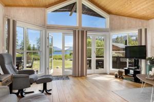 ein Wohnzimmer mit großen Fenstern und einem Flachbild-TV in der Unterkunft Cozy cabin w/garden, BBQ, canoe, swimming, central in Sinnes