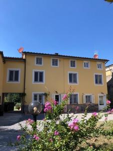 una gran casa amarilla con flores rosas delante de ella en Intero alloggio campagna Lucca en Capannori