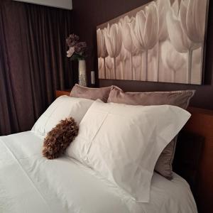 a teddy bear laying on a white bed with pillows at Casa da Praça in Miranda do Douro