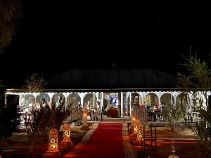 a marquee with a red carpet and lights at night at Sahara Majestic Luxury Camp in Merzouga